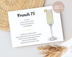 a card with the words french 75 on it next to a straw hat and flowers