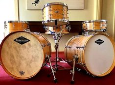 a drum set sitting on top of a carpeted floor next to a painting hanging on the wall