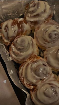 there are many cinnamon rolls on the plate and one has frosted icing in it