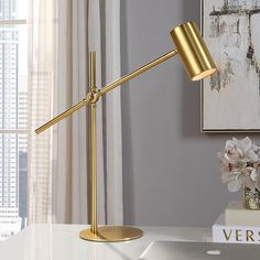 a desk lamp sitting on top of a white table next to a vase with flowers