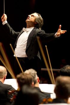 conductor in black suit and white shirt with arms outstretched