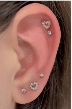 three heart shaped ear piercings on the side of a woman's ear with diamonds