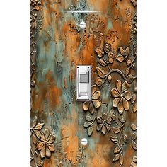 a decorative light switch cover with flowers and leaves painted on the side of an old metal door