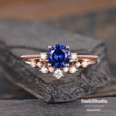 a blue and white diamond ring sitting on top of a rock