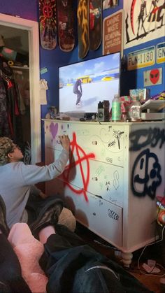 a young boy is playing with graffiti on the side of a dresser in his bedroom