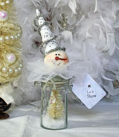 there is a snowman in a glass jar next to a christmas tree and other decorations