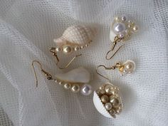 several seashells and pearls are laying on a white cloth with gold earwires