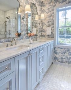 a large bathroom with two sinks, mirrors and lights on the side of the wall