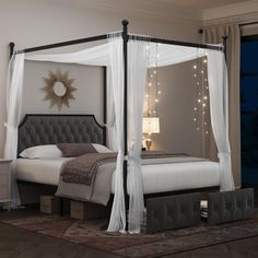 a bed with white curtains and lights on the headboard, in a bedroom setting