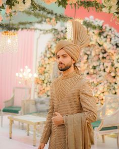 a man in a turban standing under a flower covered canopy