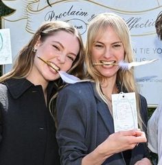 three people posing for the camera with fake toothbrushes in their mouths and one person holding up a piece of paper