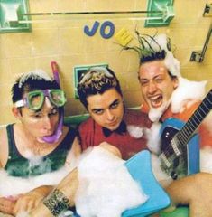 three young men are in the bathtub with foam on their heads and one is holding an electric guitar