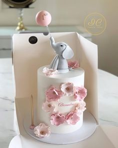 a white cake with pink flowers and an elephant on top