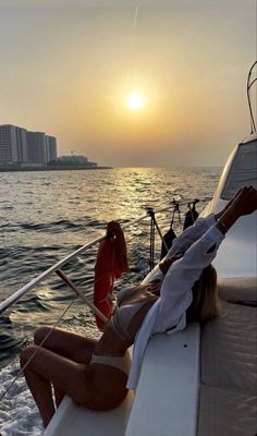 a woman laying on the back of a boat at sunset