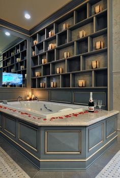 a bathroom with a large jacuzzi tub surrounded by shelves filled with candles and vases