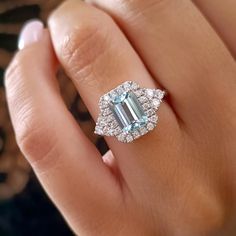 a woman's hand with a ring on it and an emerald stone in the middle