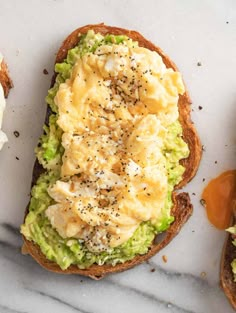 an open face sandwich with eggs and avocado on it sitting on a marble surface