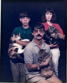 three people and two cats are posing for a photo with the caption cat on their chest