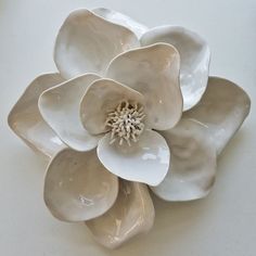 a white ceramic flower is sitting on a table top with its petals open and ready to be used as a wall decoration