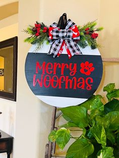 a merry and christmas sign hanging from the side of a wall next to a potted plant