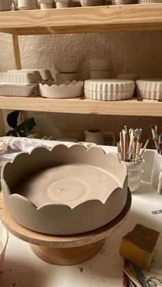 there is a bowl on the table with other bowls in the background and paintbrushes next to it