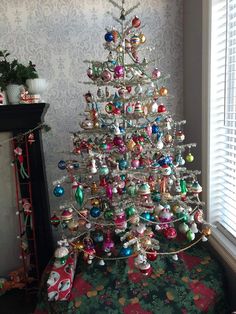 a white christmas tree with ornaments on it in front of a wallpapered room