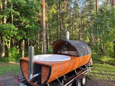 an outdoor hot tub on the back of a trailer in front of some tall trees