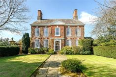 a large brick house with lots of windows on it's front lawn and landscaping