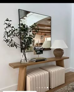 there is a mirror on the wall next to a table with two stools and a plant