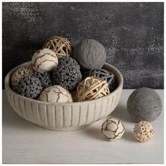 a bowl filled with lots of different types of balls on top of a white table