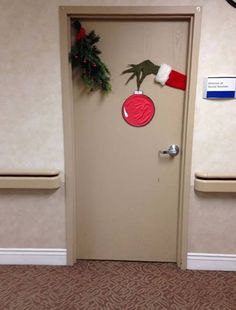 a door decorated for christmas with a santa hat and handprinted ornament