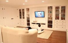 a child sitting on the floor in front of a tv and bookshelves, watching television