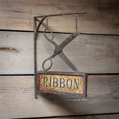 a pair of scissors hanging from the side of a sign that says ribbon on it