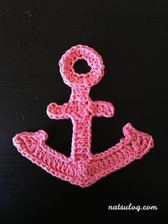 a crocheted pink anchor on a black background