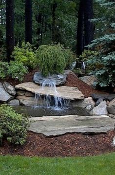 a small waterfall in the middle of a rock garden