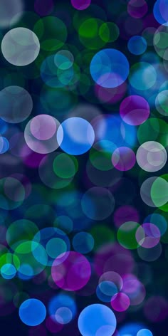 an abstract photo of blue, green and purple circles on a black background with blurry lights