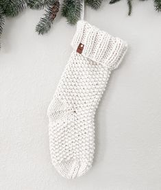 a white knitted stocking hanging from a christmas tree