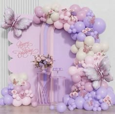 a birthday party with balloons, flowers and butterflies on the front wall is decorated in pastel colors