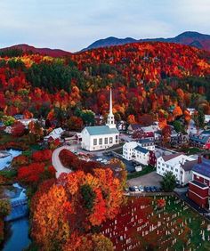 an aerial view of a small town surrounded by mountains and trees in the fall colors