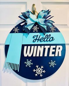 a hello winter door hanger with blue ribbon and snowflakes on the front