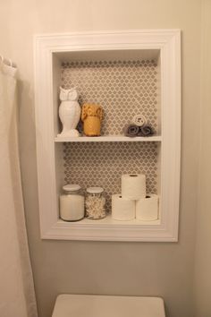 a white toilet sitting in a bathroom next to a shelf