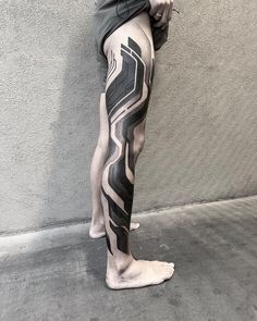 a man's leg with black and white lines on it, next to a wall