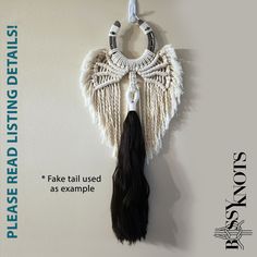 a white wall hanging with black tassels and an angel's wing on it