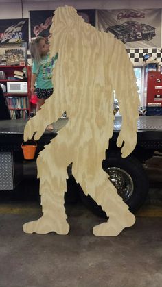 a bigfoot standing in front of a truck with a child looking at it's back