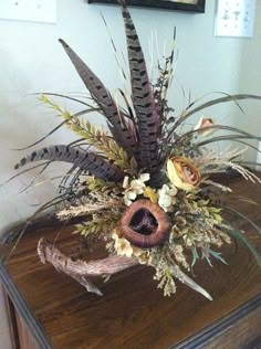 a wooden table topped with a vase filled with lots of flowers and plants on top of it