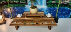 a wooden table topped with vases filled with flowers and rocks next to a painting