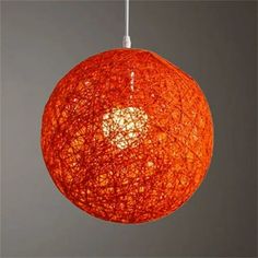 an orange ball hanging from a white cord on a gray background with the light turned on