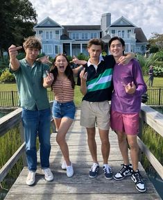 three young people standing on a wooden bridge posing for the camera with their fingers in the air