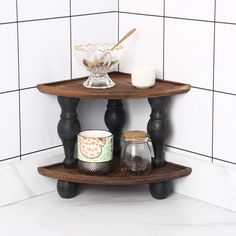 two tiered shelves in the corner of a white tiled room with candles and jars