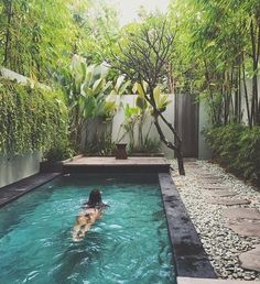 a person swimming in a small pool surrounded by greenery